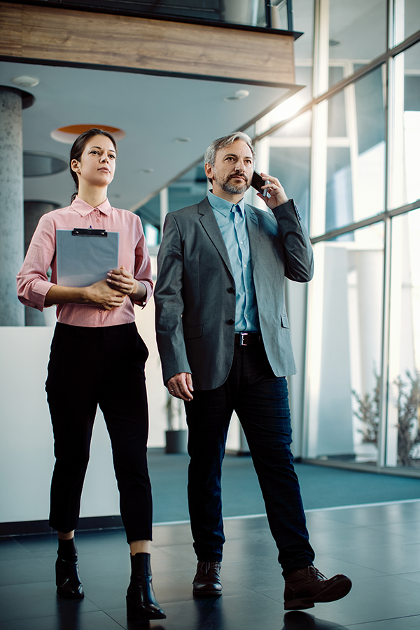 full-length-business-colleagues-walking-through-hallway-office-building